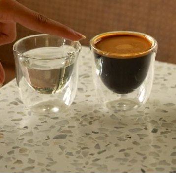 Espresso next to a glass of water on terrazzo